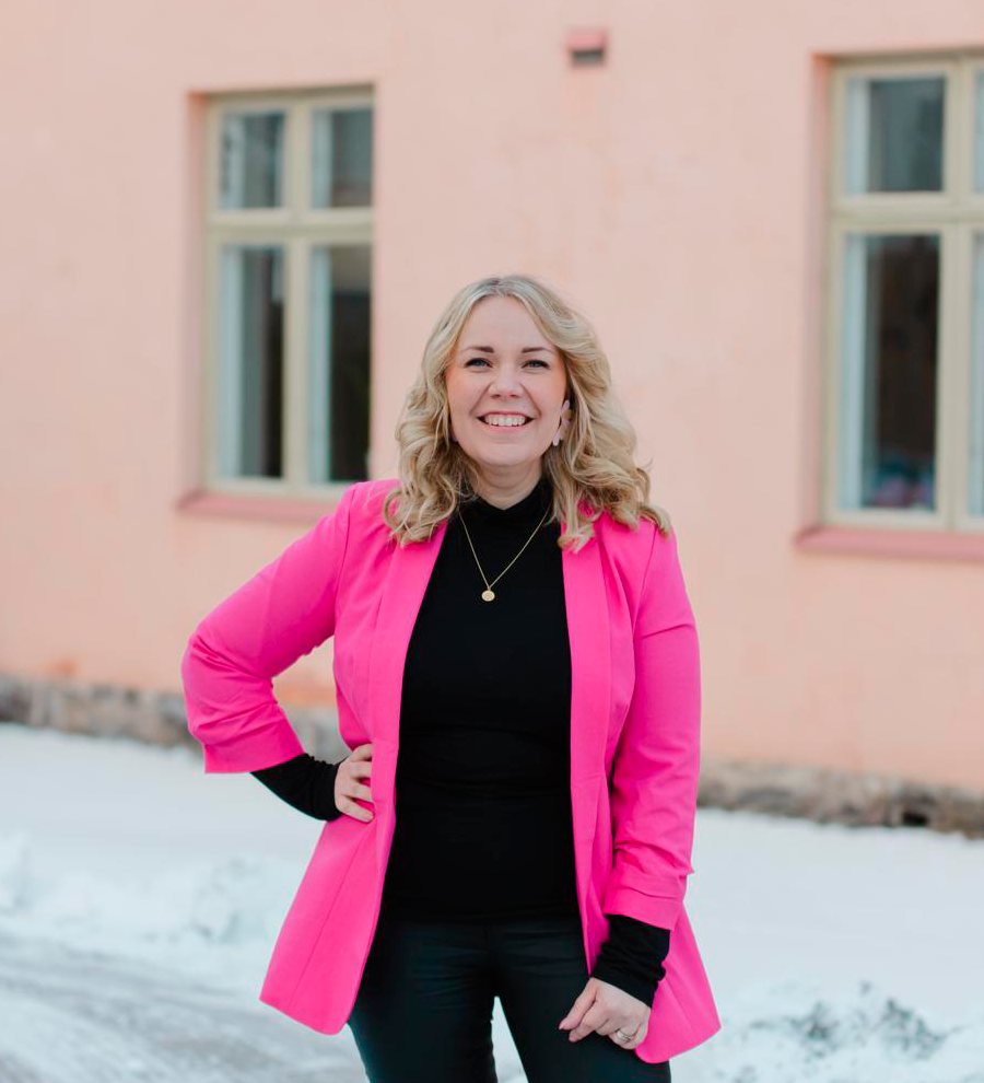 Heidi kirjaston sisäpihalla pinkissä jakussa ja hymyssä suin